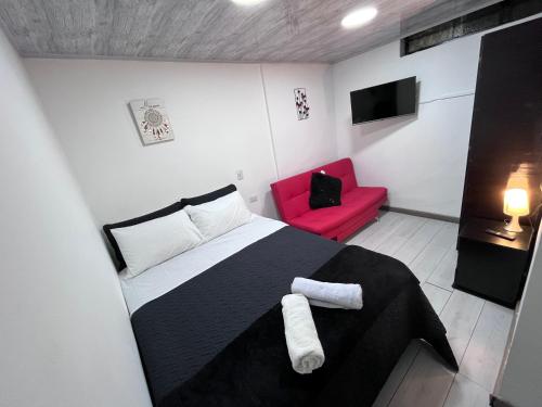 1 dormitorio con 1 cama en blanco y negro y 1 silla roja en Ayenda Edificio SantaMarta Medellín, en Medellín