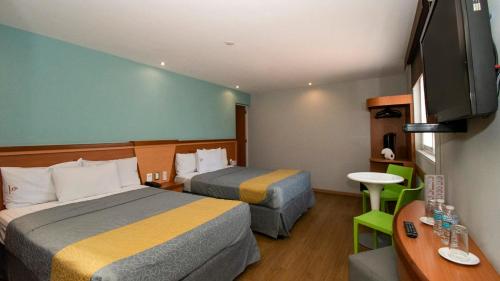 a hotel room with two beds and a flat screen tv at Hotel El Conde Naucalpan Only Adults in Mexico City