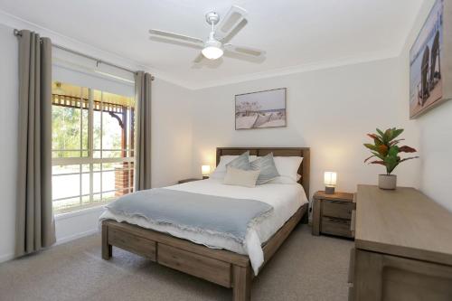 a white bedroom with a bed and a window at Tranquil Times in Tea Gardens