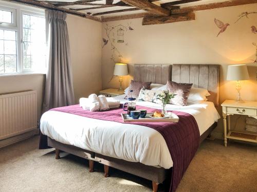 a bedroom with a large bed with a tray of food on it at Beehive Cottage in Wittersham