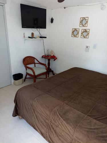 a bedroom with a bed and a chair and a flat screen tv at Sandy's room in Cancún