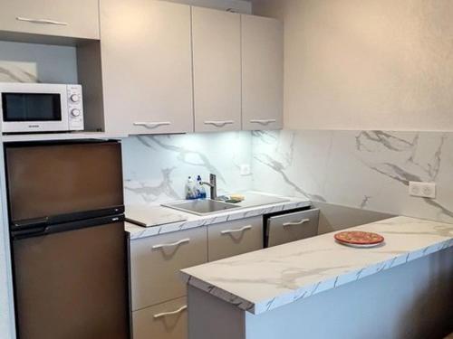 une cuisine avec des armoires blanches et un comptoir dans l'établissement T2 cabine avec terrasse à La Favière, proche plages et commerces - FR-1-610-20, à Bormes-les-Mimosas