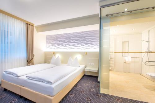 a bedroom with a large bed and a shower at Hotel Hennies in Isernhagen