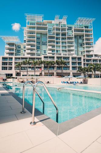 a swimming pool in front of a large apartment building at Pelican Waters Golf Resort Sunshine Coast in Caloundra