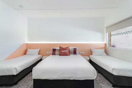 two twin beds in a room with a window at Bel Air Motel in Mackay