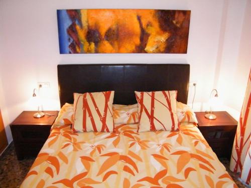 a bedroom with a bed with two night stands and a painting at Apartamentos Milenio in Cullera