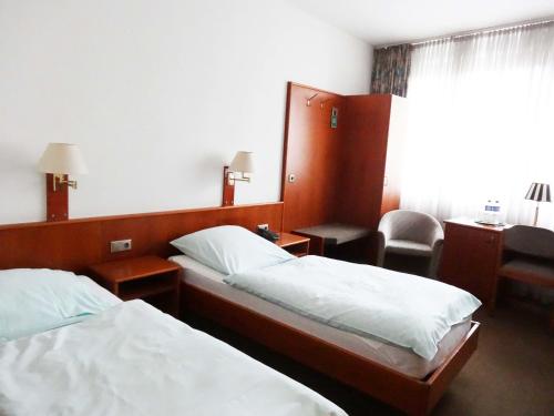 a hotel room with two beds and a desk at Zentral Hotel Poststuben in Krefeld