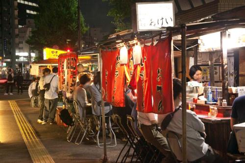 a group of people sitting at tables at a food stand at Reisenkaku Hotel Kawabata in Fukuoka