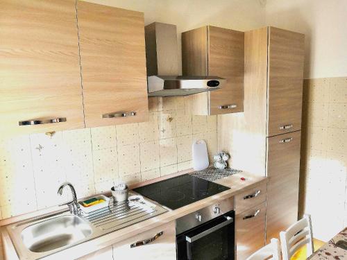 Una pequeña cocina con gabinetes de madera y un fregadero. en Novara Suite, en Novara