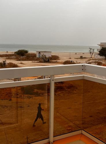 a man walking on the beach with the ocean in the background at Rufisque Dakar in Mbaw