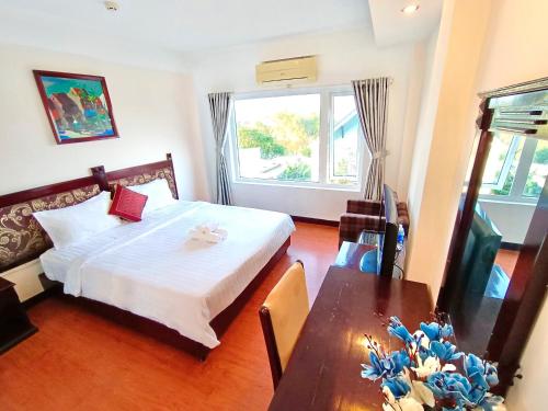 a bedroom with a bed and a table and a window at Việt Nam Hotel in Hue