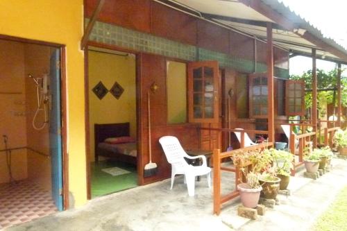 a house with a white chair sitting outside of it at Cheers Garden Chalet in Kampung Tekek