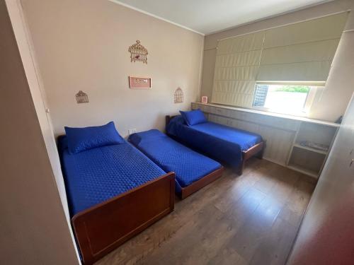 two beds in a small room with blue pillows at Conforto e simplicidade no centro da cidade in Santana do Livramento