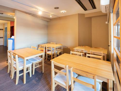 una sala da pranzo con tavoli e sedie in legno di Tabist Hotel Rakuserina a Fuefuki