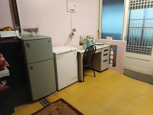 eine Küche mit 2 Kühlschränken, einem Waschbecken und einem Tisch in der Unterkunft Ruishi Homestay in T'ai-ping