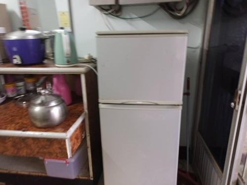 una nevera blanca en una cocina junto a un estante en Ruishi Homestay, en T'ai-ping