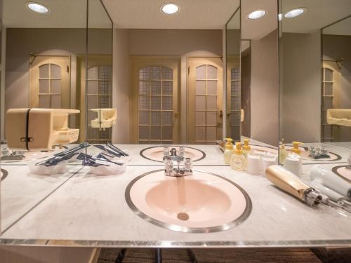 bagno con lavandino e grande specchio di Tabist Hotel Rakuserina a Fuefuki