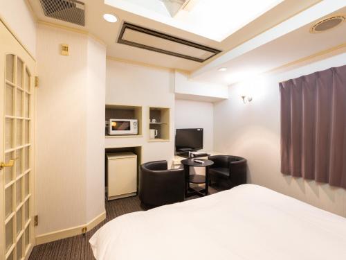 a hotel room with a bed and chairs and a desk at Tabist Hotel Rakuserina in Fuefuki