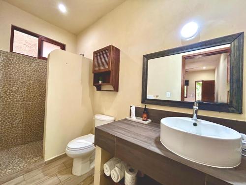 a bathroom with a sink and a toilet and a mirror at Aldea Xaan Ha Tulum in Tulum