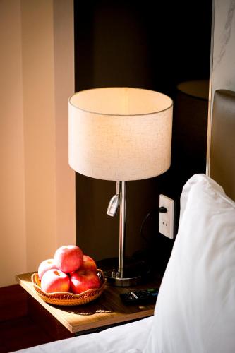 a table with a lamp and a plate of fruit on it at Aloha Hotel Quy Nhơn in Quy Nhon