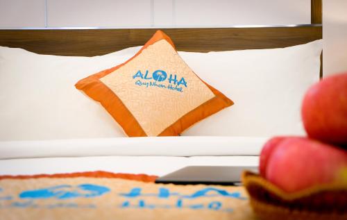 a sign on a bed with apples on a table at Aloha Hotel Quy Nhơn in Quy Nhon