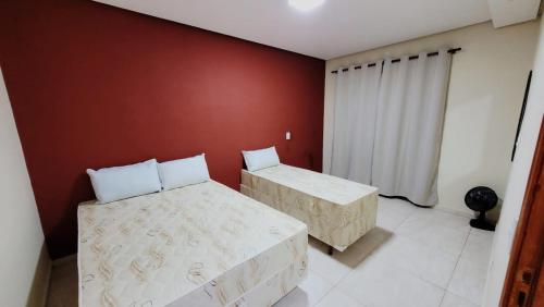 a bedroom with two beds and a red wall at Apartamento Aparecida Rone 2 in Aparecida