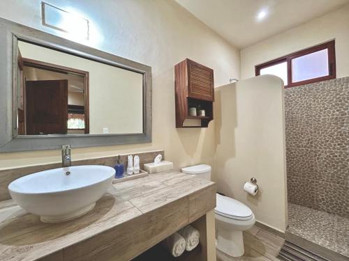 a bathroom with a sink and a toilet and a mirror at Aldea Xaan Ha Tulum in Tulum