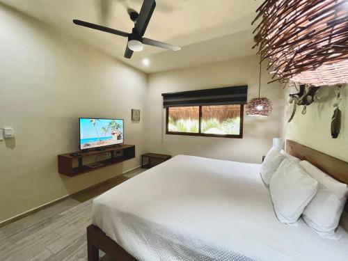a bedroom with a bed with a ceiling fan and a tv at Aldea Xaan Ha Tulum in Tulum