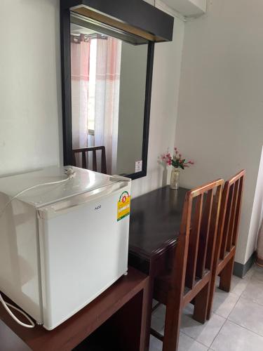 a kitchen with a table and a white refrigerator at Win Mansion in Bangkok