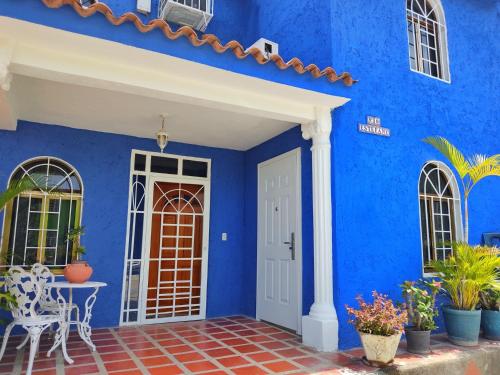 ein blaues Haus mit einer weißen Tür und einer Terrasse in der Unterkunft BELLA SUITE frente al Aeropuerto in Catia La Mar
