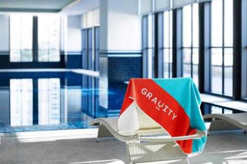 a chair with a book on it next to a pool at GRAVITY JOSUN Seoul Pangyo, Autograph Collection in Seongnam