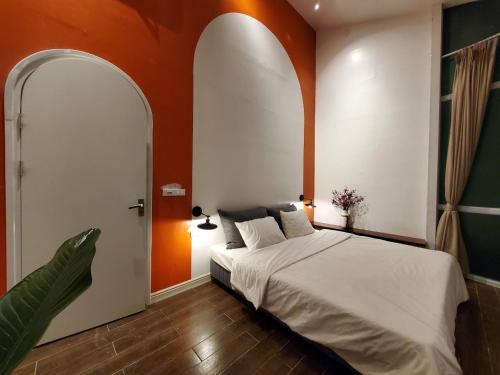 a bedroom with a white bed and an orange wall at Le vent Tam Đảo homestay in Tam Ðảo