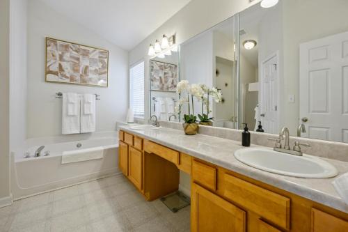 a bathroom with a sink and a tub and a mirror at Spacious Serene 3BR Near LakePoint & DT Acworth in Acworth