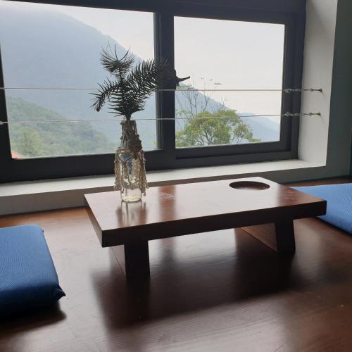 a vase on a table in front of a window at Le vent Tam Đảo homestay in Tam Ðảo