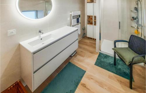 ein Badezimmer mit einem Waschbecken, einem Stuhl und einem Spiegel in der Unterkunft Stunning Home In Plouguerneau With Kitchen in Plouguerneau