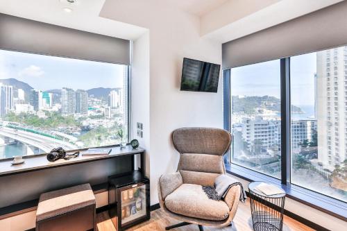 a living room with a chair and a large window at Urbanwood Ap Lei Chau in Hong Kong
