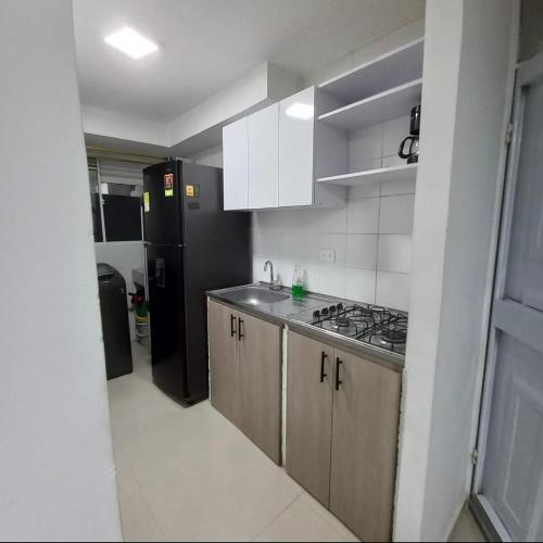 a kitchen with a sink and a black refrigerator at Apto nuevo, amoblado sector tranquilo, buen precio in Barranquilla