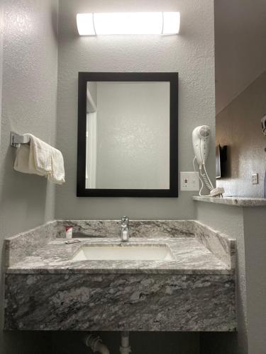 a bathroom with a marble sink and a mirror at Copper Manor Motel in Silver City