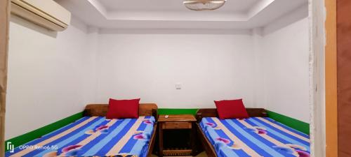 2 Betten in einem Zimmer mit roten und blauen Kissen in der Unterkunft Family Guesthouse in Koh Rong