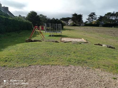 a playground in the middle of a grassy field at Chalet Familial en Bois à 150 m de la Mer in Santec