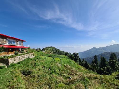 a house on the side of a hill with mountains at The Rosly Estate in Kanatal