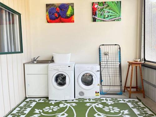 a laundry room with a washer and dryer on a rug at CandE’s Guesthouse in Kingscote