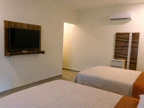 a room with two beds and a flat screen tv at HOTEL ISLA in Isla Aguada