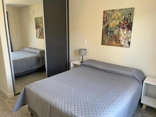 Dormitorio pequeño con cama y espejo en Complejo de departamento lencinas en Godoy Cruz