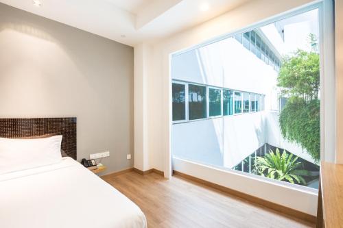 a bedroom with a bed and a large window at Village Hotel Changi by Far East Hospitality in Singapore