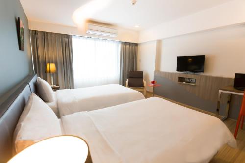 a hotel room with two beds and a television at Grand Tower Inn Sathorn Hotel in Bangkok