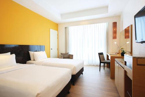a hotel room with two beds and a desk at Village Hotel Changi by Far East Hospitality in Singapore