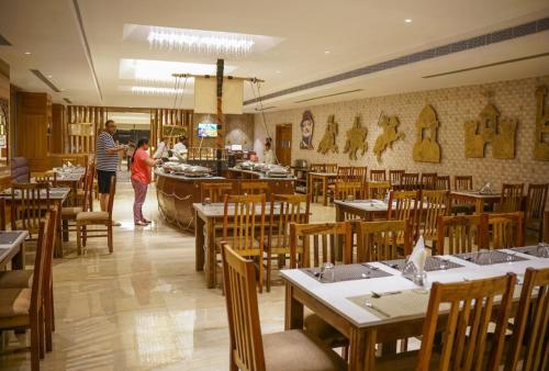 a restaurant with wooden tables and chairs and a man and a woman at Hotel Paandora Grand,Udaipur in Udaipur