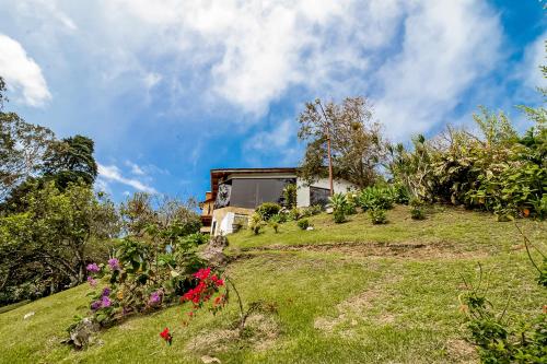 a house on top of a grassy hill with flowers at Montana Zurqui in San José de la Montaña