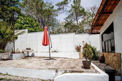 a red umbrella sitting in a yard next to a fence at Montana Zurqui in San José de la Montaña